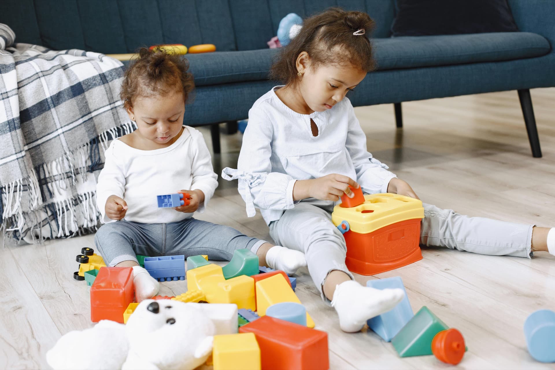Two children playing with blocks on the living room floor